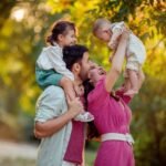 Family day! happy parents mom and dad are holding their son and daughter in the arms of their young children_ they laugh and have fun in the summer on a walk in the park _ Premium Photo